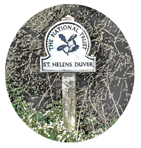 metalic sign on wooden post surrounded by greenary